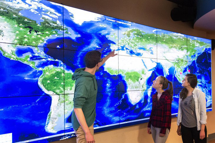 electronic map wall with students in front of it