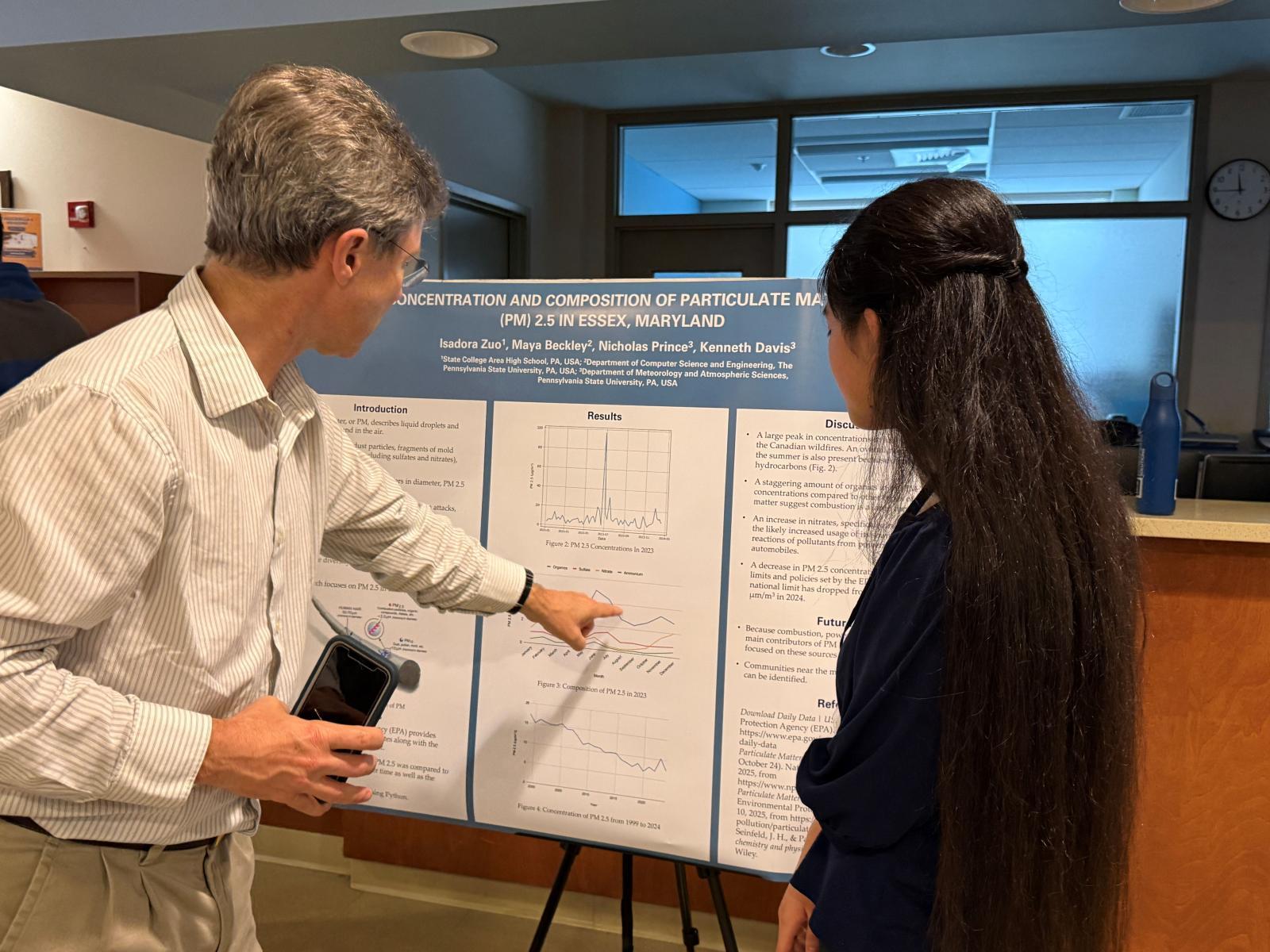 Ken Davis (left) and student Isadora Zuo in front of a poster. 