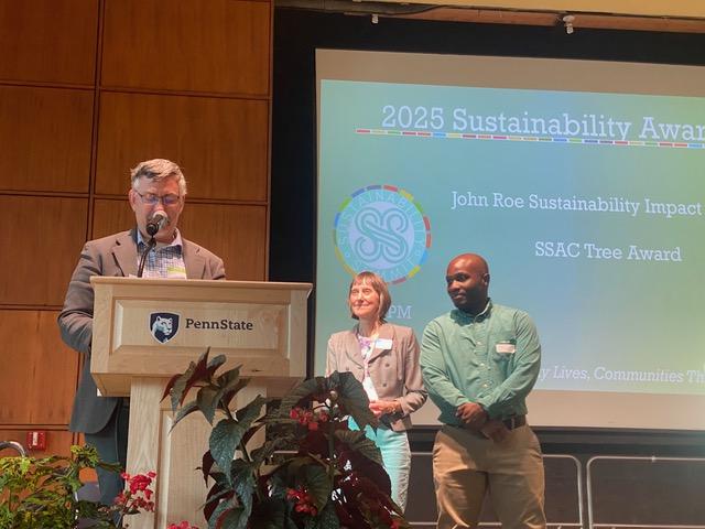Eliott Foust on stage receiving the 2025 John Roe Sustainability Impact Award